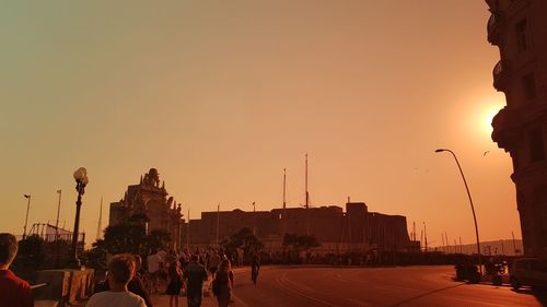 People on street against sky during sunset