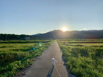 Road amidst field against clear sky