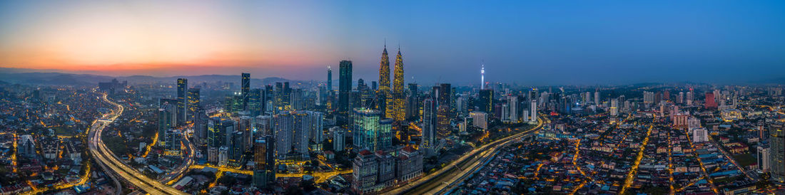 Panoramic view of modern buildings in city against sky during sunset