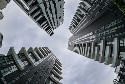 Directly below shot of buildings against cloudy sky