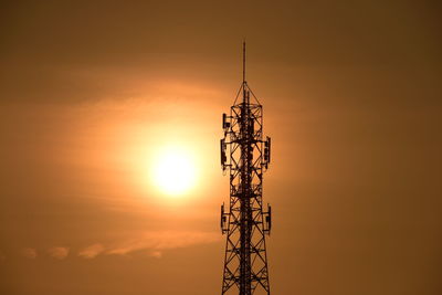 Silhouette of communications tower against sky during sunset