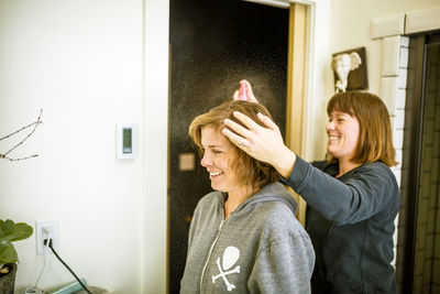 Woman using hairspray on sister's hair