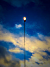 Low angle view of illuminated street light against sky