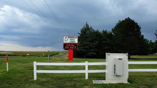 Information sign on field against sky