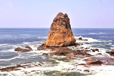 Rock formation on beach against clear sky