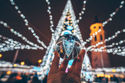 Person holding illuminated carousel at amusement park