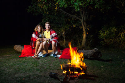 Young couple sitting on bonfire at night