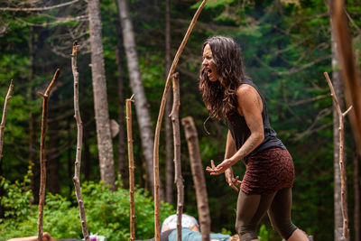 Full length of woman standing by tree in forest