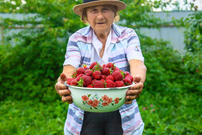 Portrait of senior woman holding bowl of strawberries