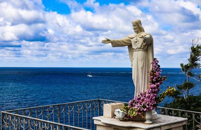 Statue by sea against sky