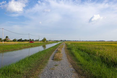 Road amidst field against sky