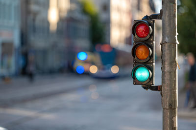 Blurred view of city traffic with traffic lights, in the foreground a semaphore with a green light