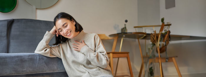 Portrait of young woman sitting on chair at home