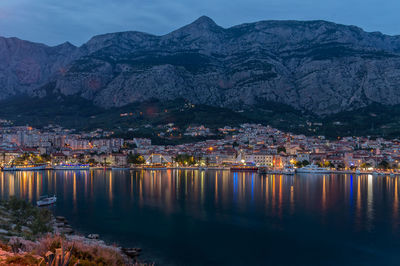 River by illuminated town against sky at night