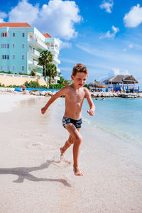 Full length of boy playing on beach against sky