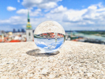 Close-up of crystal ball on beach against sky