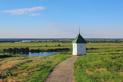 Chapel on grassy field against blue sky