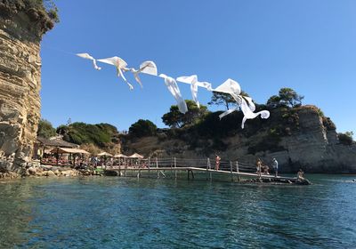 People in sea against clear blue sky