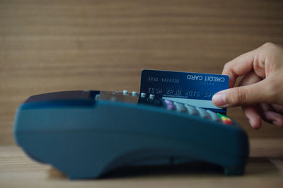 Close-up of hand holding smart phone on table