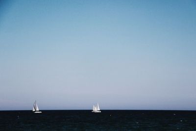 Sailboat sailing on sea against clear sky