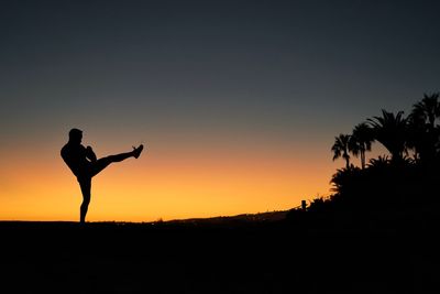 Low angle view of silhouette man standing against sky during sunset