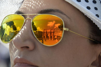 Woman wearing sunglasses with reflection of buildings in city