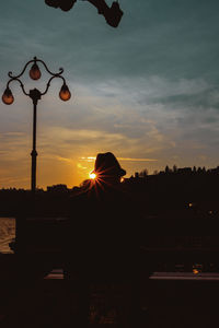 Silhouette street lights against sky during sunset
