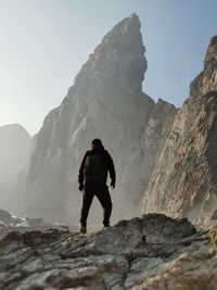 Rear view of man walking on rocks against mountains