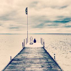 Pier on sea against cloudy sky