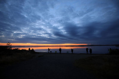 Silhouette people on beach against sky during sunset