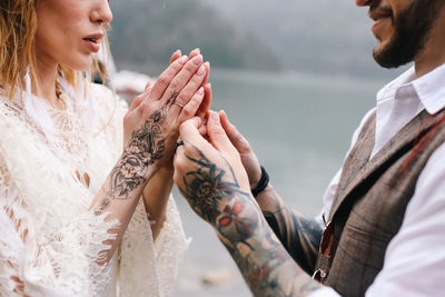 A man and a woman in love hold their tattooed hands and look at each other at the wedding
