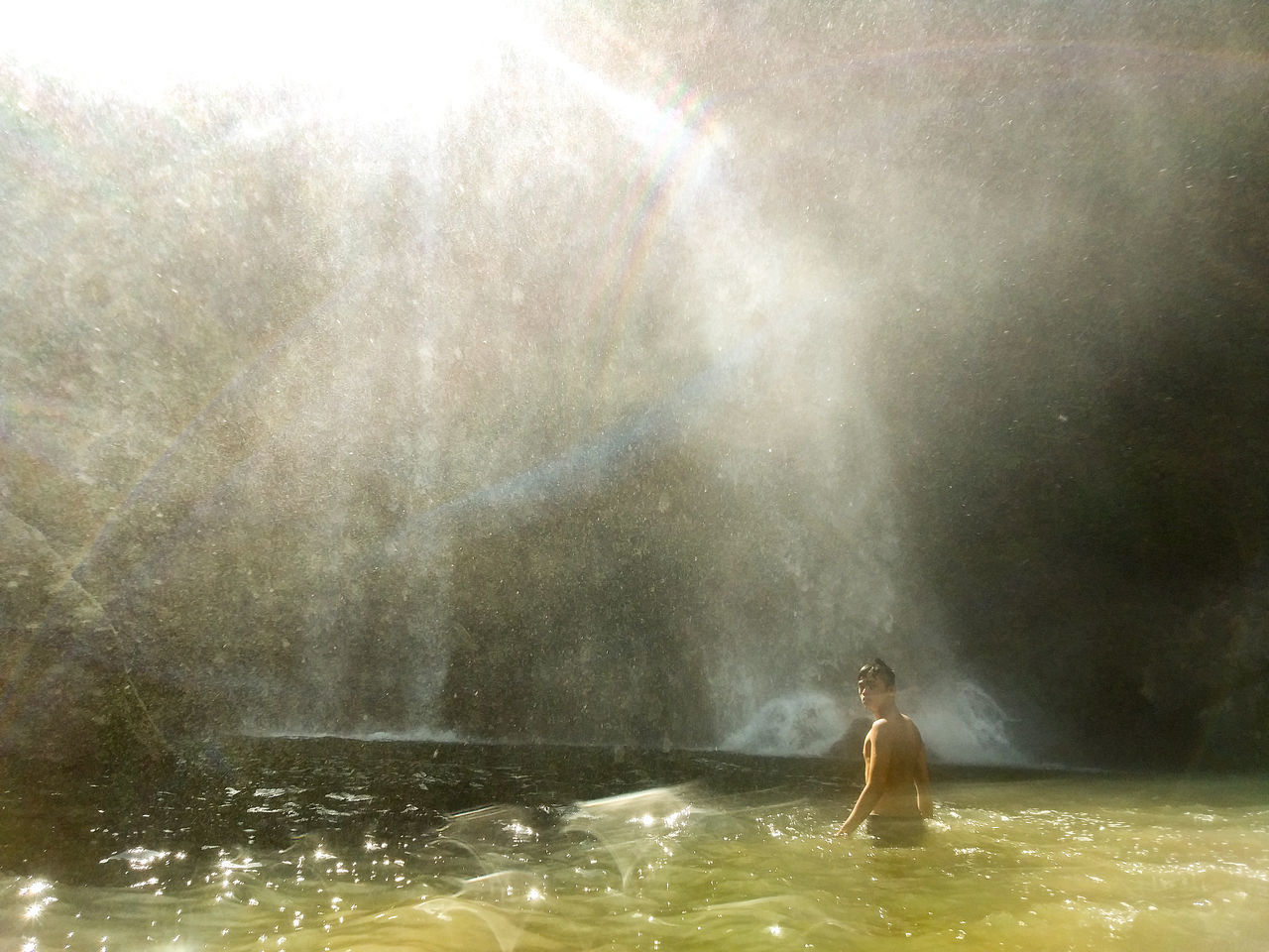 WOMAN IN WATER AT WATERFALL