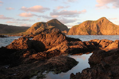 Rock formation on beach against sky