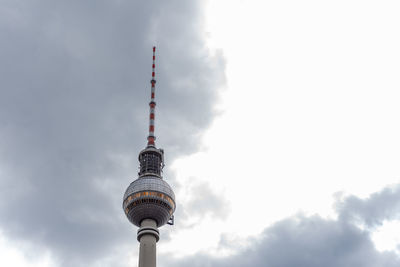 Low angle view of communications tower against cloudy sky