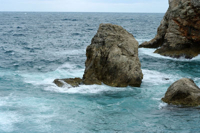 Rock formation in sea against sky