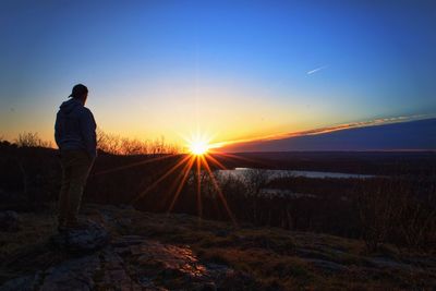 Full length of man on hill standing against blue sky during sunset