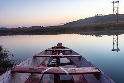 Traditional wood boat at calm lake with dramatic sunrise colorful sky reflection at morning