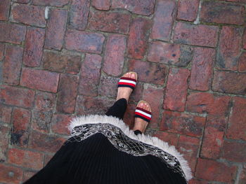 Low section of woman walking on brick road