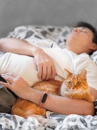 Cat is lying in bed with its owner. healing power of animals. sick man with fluffy pet in bedroom.
