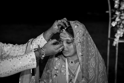 Midsection of couple were the groom puts sindoor on the hair  of his bride.
