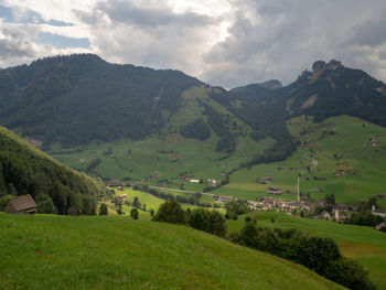 Scenic view of green landscape and mountains against sky