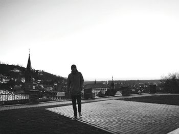 Man walking on railing against sky
