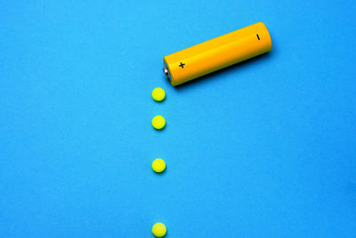 High angle view of battery with balls on blue background