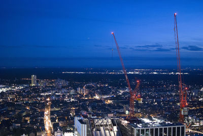 Illuminated cityscape by sea against clear blue sky at night