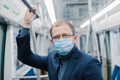 Portrait of businessman wearing mask in subway train