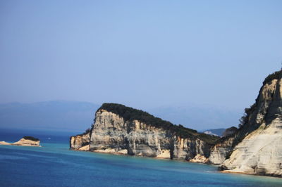 Scenic view of sea and mountains against clear blue sky