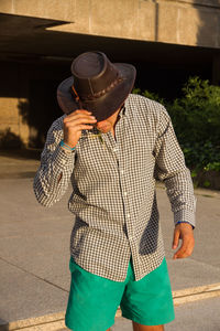 Man wearing hat standing on footpath