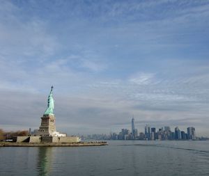 Statue of liberty by hudson river against sky