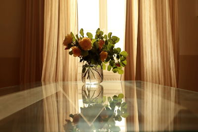 Flower vase on table by window at home