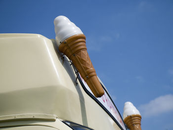 Low angle view of artificial ice cream on truck against sky